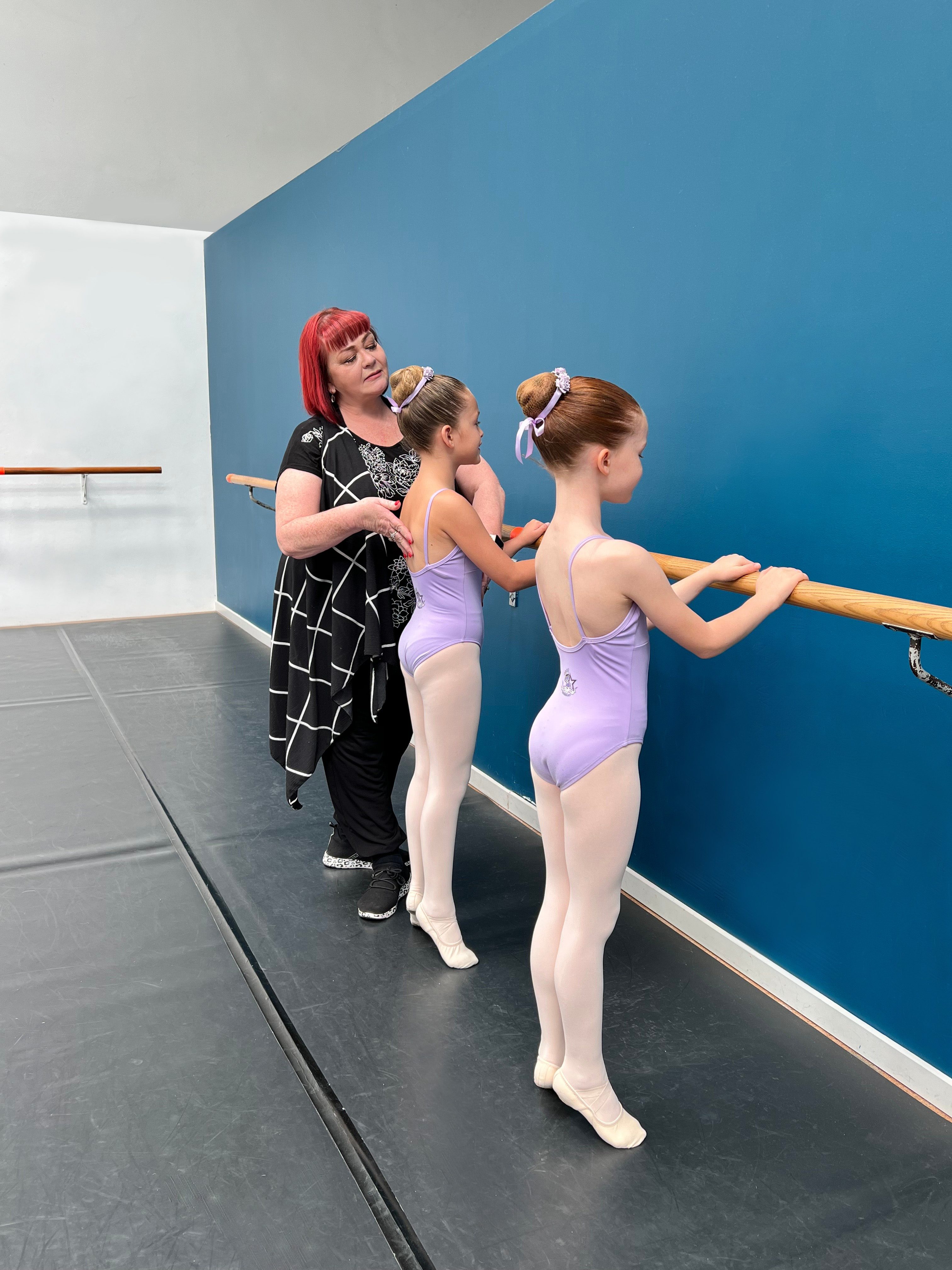 Teacher helping students in ballet class at Simone's School of Performing Arts in Berkeley Vale, working on correct technique.