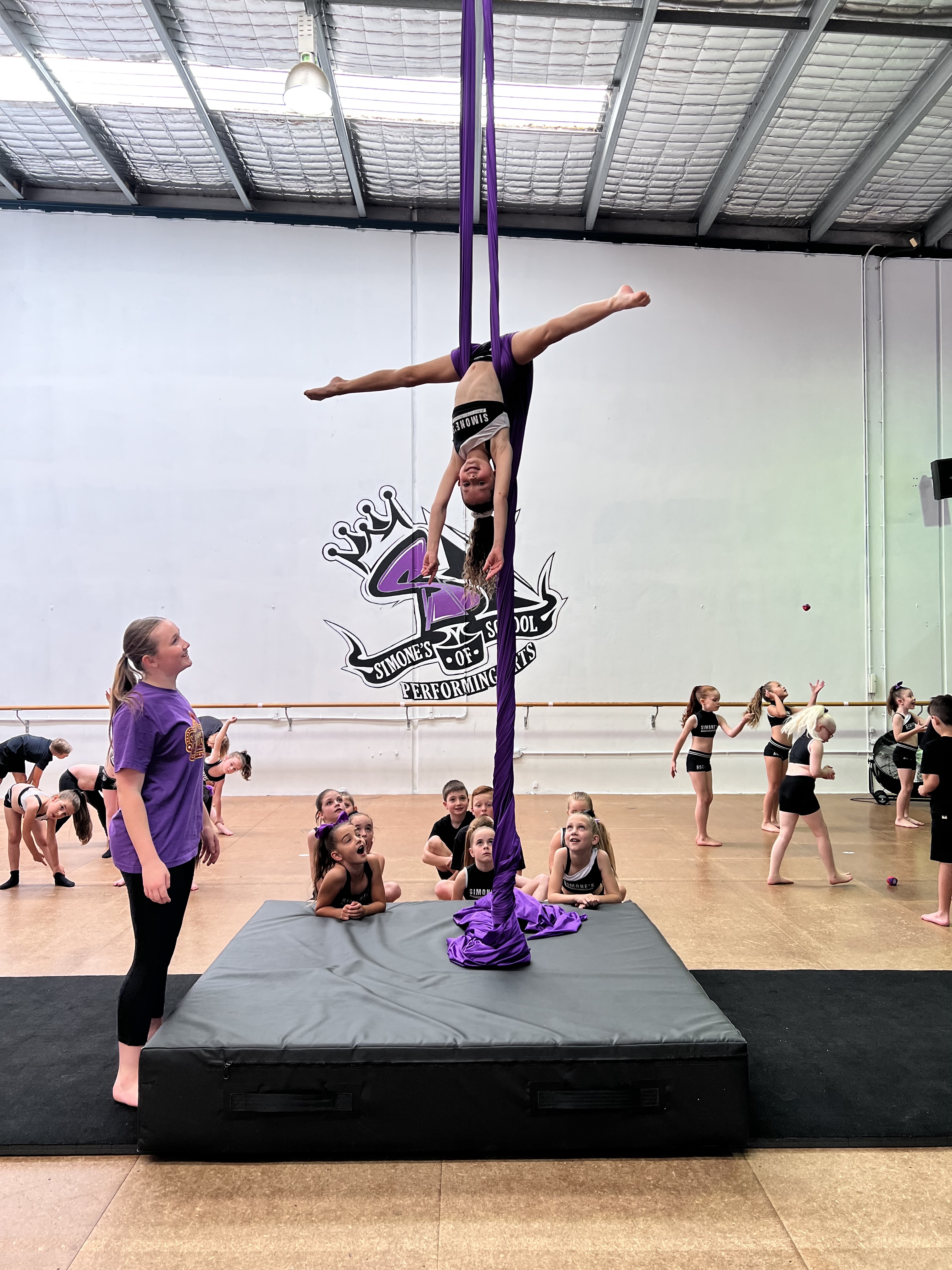 Teaching helping student learn trapeze in circus classes at Simone's School of Performing Arts Berkeley Vale.